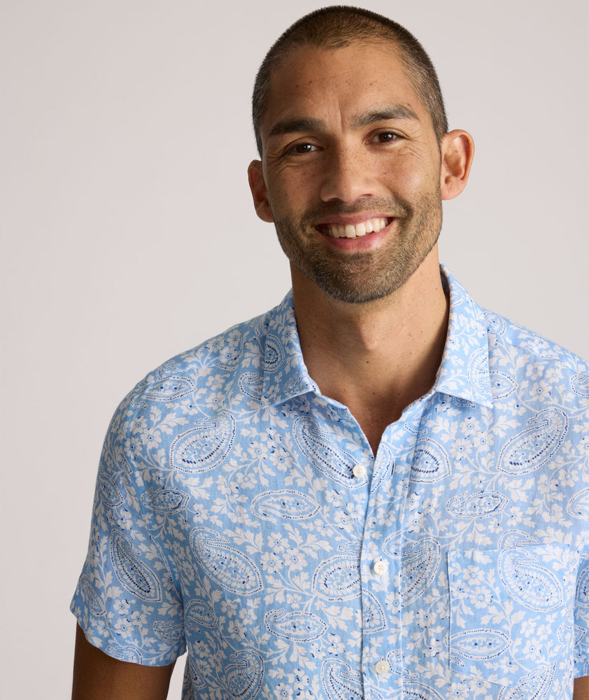 Model is wearing UNTUCKit Turner short sleeve linen shirt in light blue print. 
